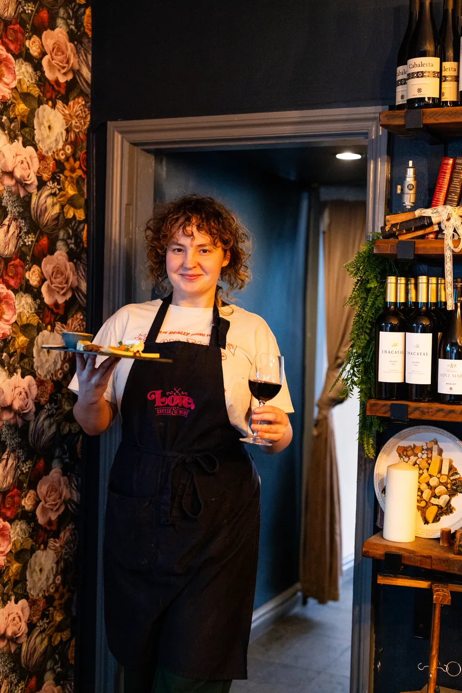 A member of the team serving a board and a glass of wine