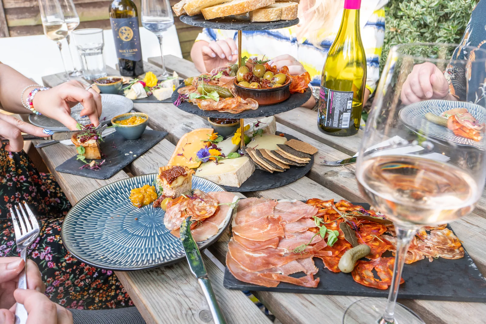 A spread of charcuterie, cheese and wine shared around the table at The Speakcheesey