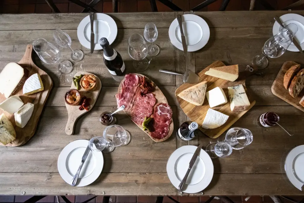 How to Make a Charcuterie Board: A Cheesemonger's Guide 4 A table laid with separate boards of cured meats, cheeses and pork pies